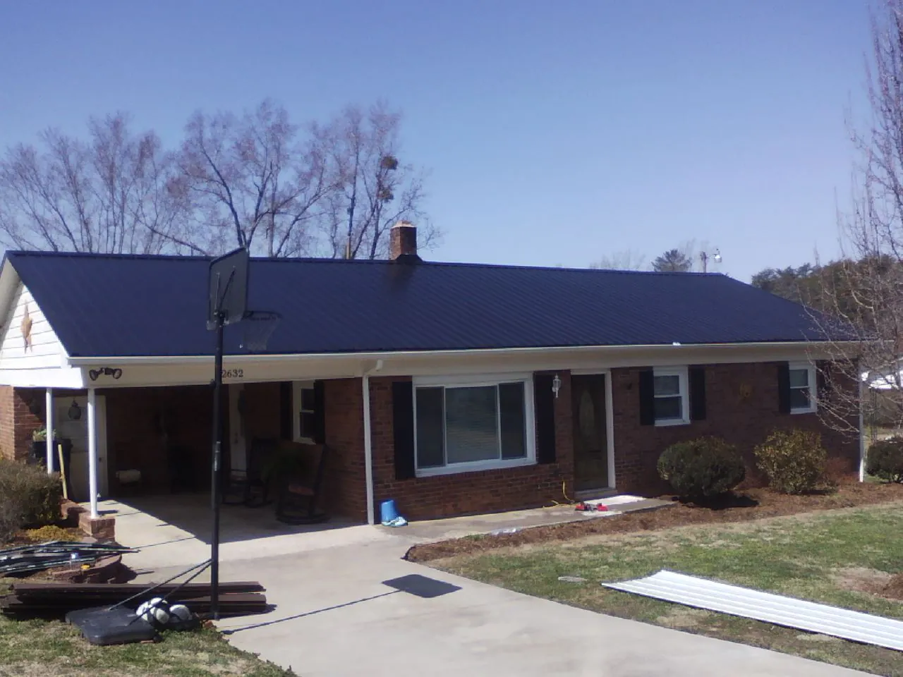 Finished dark blue metal roof on a brick ranch with a carport in Belvidere