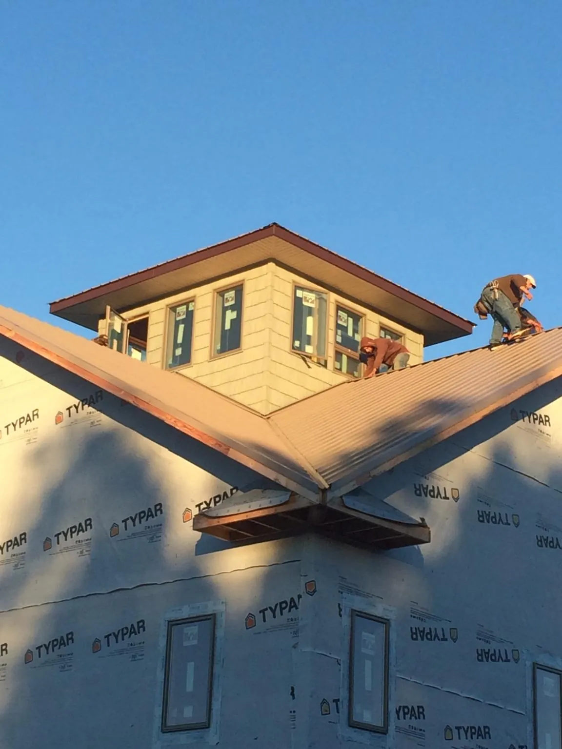 Roofers working around a rooftop cupola on a new metal roof at sunset — Roof Waterproofing in Belvidere by Roofing Brothers